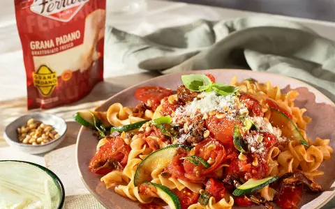 Pasta mit Tomaten, Zucchini und Pinienkernen, bestreut mit Grana Padano. Diese Parmesan-Sorten verfeinern jedes Gericht.