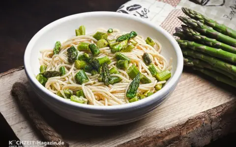 Eine Schüssel mit Spaghetti und frischem Spargel, dane liegt ein Bund grüner Spargel. Ein köstliches Gericht, das Lust auf mehr macht.