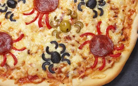 Gruselige Halloween-Pizza mit Spinnen aus Oliven und Salami, die über geschmolzenen Käse krabbeln.