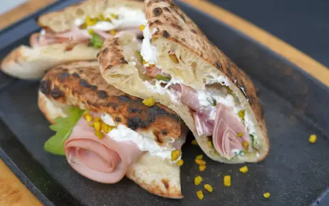 Gegrillte Pizza-Taschen gefüllt mit cremiger Ricotta, Mortadella und Pistazien.