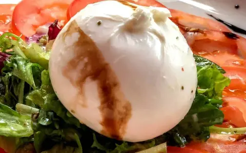 Cremige Burrata auf Tomaten und Salat, ein einfaches Gericht, das sich perfekt für Burrata Rezepte eignet.