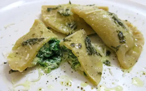 Mezzelune spinaci, gefüllt mit cremigem Spinat und Ricotta, beträufelt mit Olivenöl und bestreut mit Parmesan.