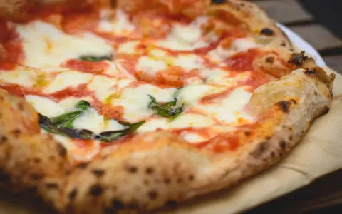 Ein frisch gebackener, italienischer Pizzateig mit geschmolzenem Mozzarella, Tomatensauce und Basilikum.