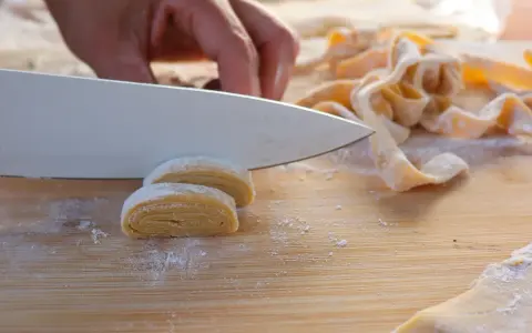 Frische Pasta wird mit einem Messer geschnitten. Der Teig muss ruhen, bevor er weiterverarbeitet wird.
