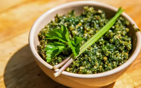 Schüssel mit würzigem Giersch Pesto, garniert mit frischen Kräutern auf Holzhintergrund.