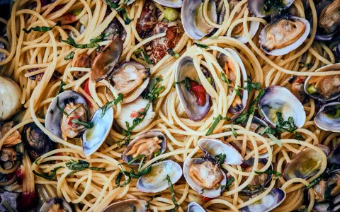 Spaghetti Vongole: Ein Teller voller goldener Spaghetti, vermischt mit frischen Venusmuscheln, Knoblauch und Kräutern.