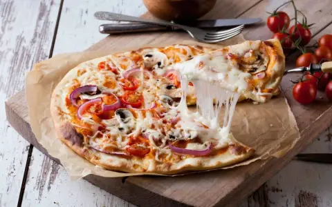 Perfekter Pizzateig Neapel, dank Thermomix! Eine dampfende Pizza mit geschmolzenem Käse, Tomaten und Pilzen wird serviert.