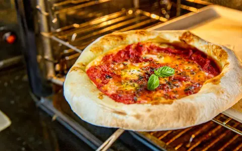 Frische Pizza Margherita mit geschmolzenem Käse und Basilikum wird im Ofen gebacken.