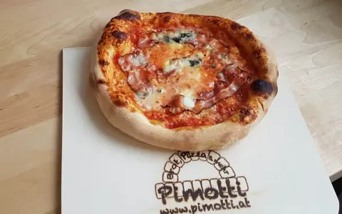 Eine knusprige Pancetta Pizza mit geschmolzenem Käse und Tomatensauce auf einem Holzbrett.