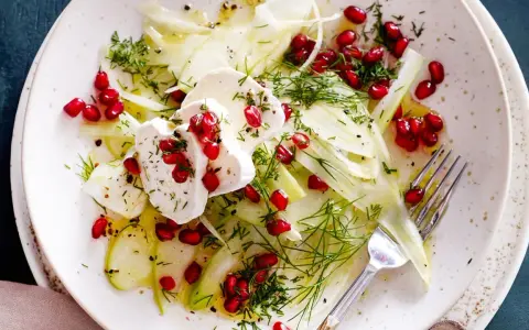 Frischer Fenchel-Apfel-Salat mit Granatapfelkernen und Ziegenkäse, garniert mit Dill. Ein leichter Genuss.