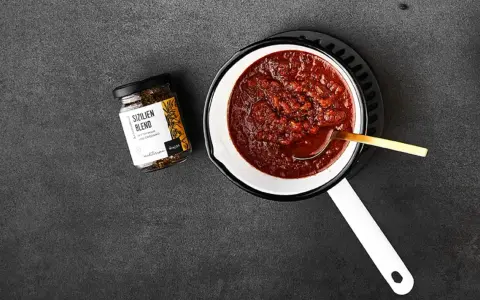 Ein Topf mit köstlichem Sugo di Pomodoro, daneben ein Glas "Sizilien Blend" Gewürzmischung. Perfekt für Pasta!