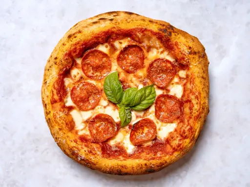 Eine köstliche New York Style Pizza mit Salami und frischem Basilikum, bereit zum Genießen.