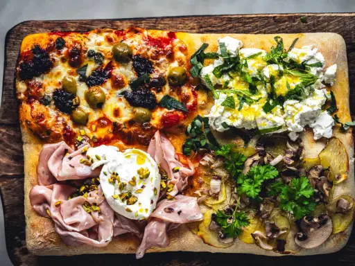 Vier verschiedene Beläge auf einer rechteckigen Pizza in Teglia: Oliven & Tomaten, Ricotta & Kräuter, Mortadella & Burrata, Kartoffeln & Pilze.