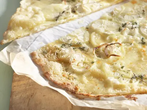 Dünne, knusprige knoblauch pizza mit geschmolzenem Käse und Zwiebelringen, garniert mit frischen Kräutern.