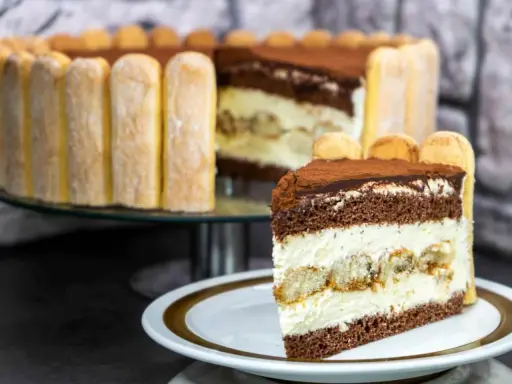 Ein Stück Tiramisu Torte mit Löffelbiskuits und Kakao bestäubt.