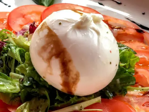 Cremige Burrata auf Tomaten und Salat, ein einfaches Gericht, das sich perfekt für Burrata Rezepte eignet.