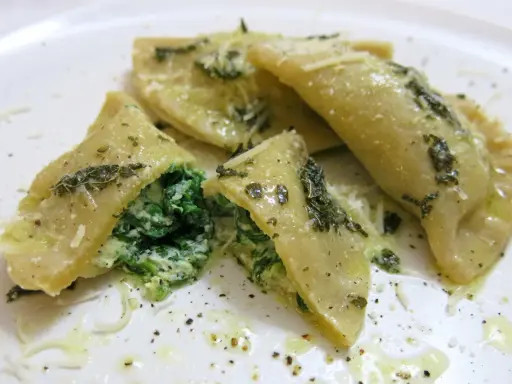 Mezzelune spinaci, gefüllt mit cremigem Spinat und Ricotta, beträufelt mit Olivenöl und bestreut mit Parmesan.