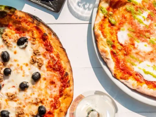 Zwei Pizzen, eine mit Thunfisch und Oliven, die andere mit Pesto. Das Geheimnis einer perfekten Pizza liegt oft im Mehl Typ 00.