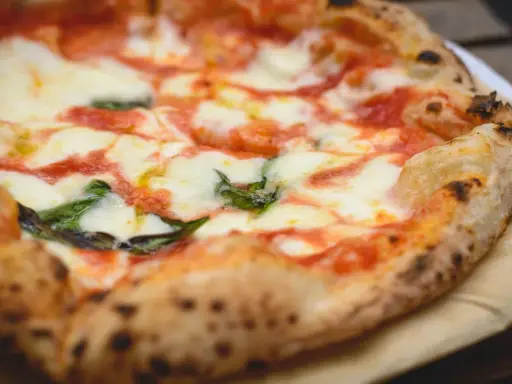 Ein frisch gebackener, italienischer Pizzateig mit geschmolzenem Mozzarella, Tomatensauce und Basilikum.
