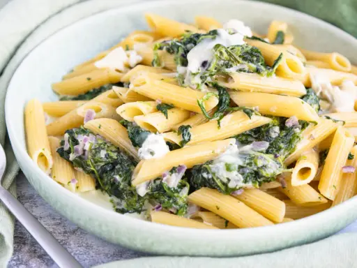 Penne-Nudeln mit cremiger Spinat-Gorgonzola-Sauce und zerbröckeltem Gorgonzola.