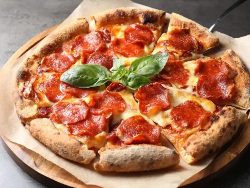 Eine köstliche Pizza mit geschmolzenem Käse und vielen Scheiben italienischer Salami, garniert mit frischem Basilikum.
