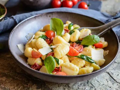 Ein köstlicher Gnocchi Salat mit Kirschtomaten, getrockneten Tomaten, frischem Basilikum und Parmesan.