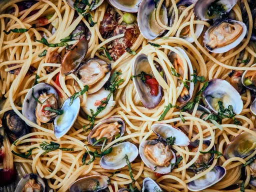 Spaghetti Vongole: Ein Teller voller goldener Spaghetti, vermischt mit frischen Venusmuscheln, Knoblauch und Kräutern.
