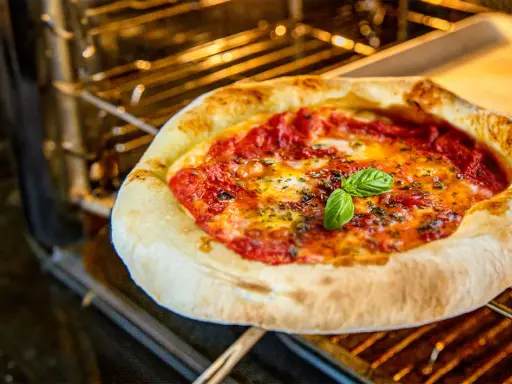 Frische Pizza Margherita mit geschmolzenem Käse und Basilikum wird im Ofen gebacken.
