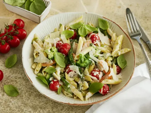 Pasta Primavera mit Penne, Brokkoli, Kirschtomaten, Spargel und Parmesan. Frisches Basilikum garniert dieses köstliche Gericht.