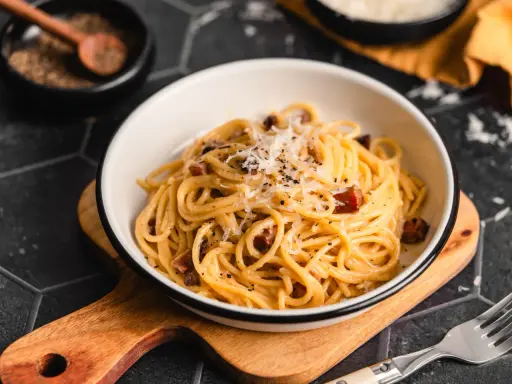 Eine Schüssel cremiger Spaghetti Carbonara, bestreut mit Parmesan und schwarzem Pfeffer, bereit zum Genießen.