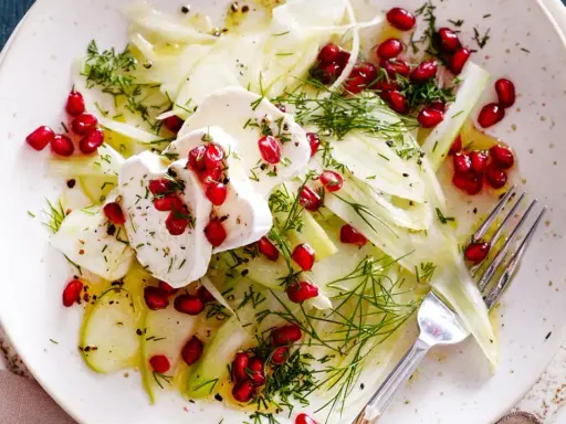 Frischer Fenchel-Apfel-Salat mit Granatapfelkernen und Ziegenkäse, garniert mit Dill. Ein leichter Genuss.