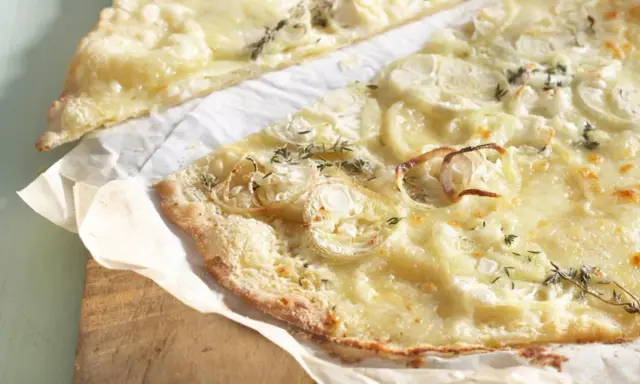 Dünne, knusprige knoblauch pizza mit geschmolzenem Käse und Zwiebelringen, garniert mit frischen Kräutern.