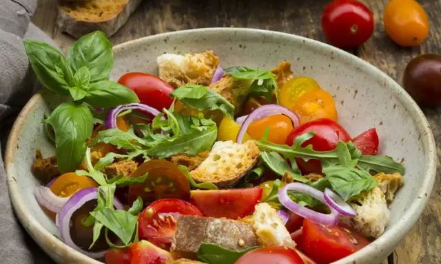 Bunter Tomatensalat mit Brotstücken, Zwiebeln und Basilikum, verfeinert mit einem Hauch Balsamico Dressing.