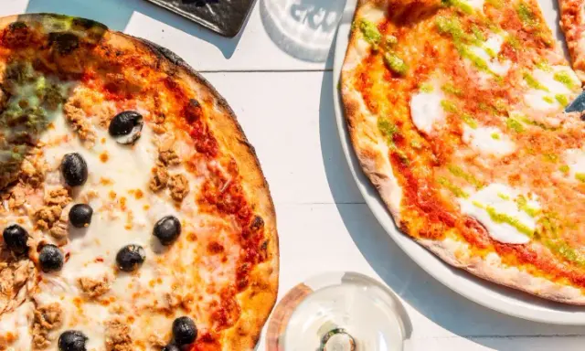 Zwei Pizzen, eine mit Thunfisch und Oliven, die andere mit Pesto. Das Geheimnis einer perfekten Pizza liegt oft im Mehl Typ 00.