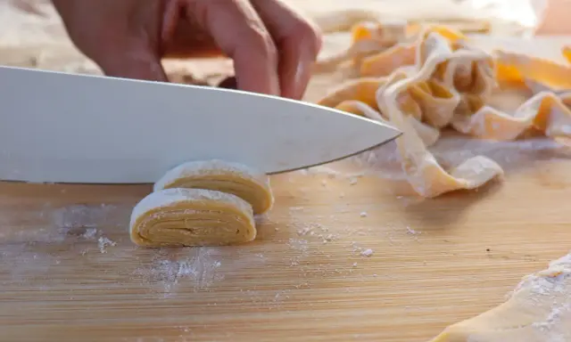 Frische Pasta wird mit einem Messer geschnitten. Der Teig muss ruhen, bevor er weiterverarbeitet wird.