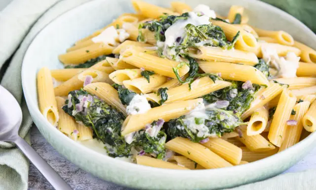 Penne-Nudeln mit cremiger Spinat-Gorgonzola-Sauce und zerbröckeltem Gorgonzola.