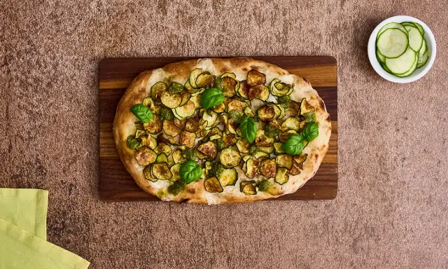 Pinsa mit Zucchini und Basilikum, ein kulinarisches Erbe, das an die Pinsa Herkunft erinnert.