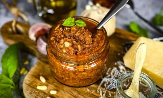 Ein Glas mit rustikalem Balsamico Pesto, garniert mit Basilikum. Daneben Pinienkerne, Knoblauch und Parmesan.