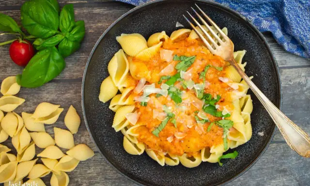 Herzhafte Muschelnudeln mit cremiger Tomaten-Sahne-Sauce, garniert mit frischem Basilikum und Parmesan. Ein Genuss!