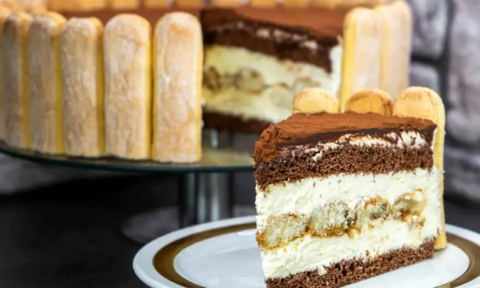 Ein Stück Tiramisu Torte mit Löffelbiskuits und Kakao bestäubt.