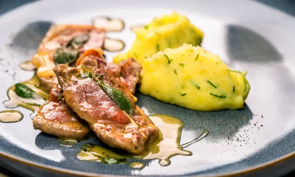 Saltimbocca alla Romana: zarte Kalbsschnitzel mit Salbei und Schinken in einer köstlichen Sauce, serviert mit cremigem Kartoffelpüree.
