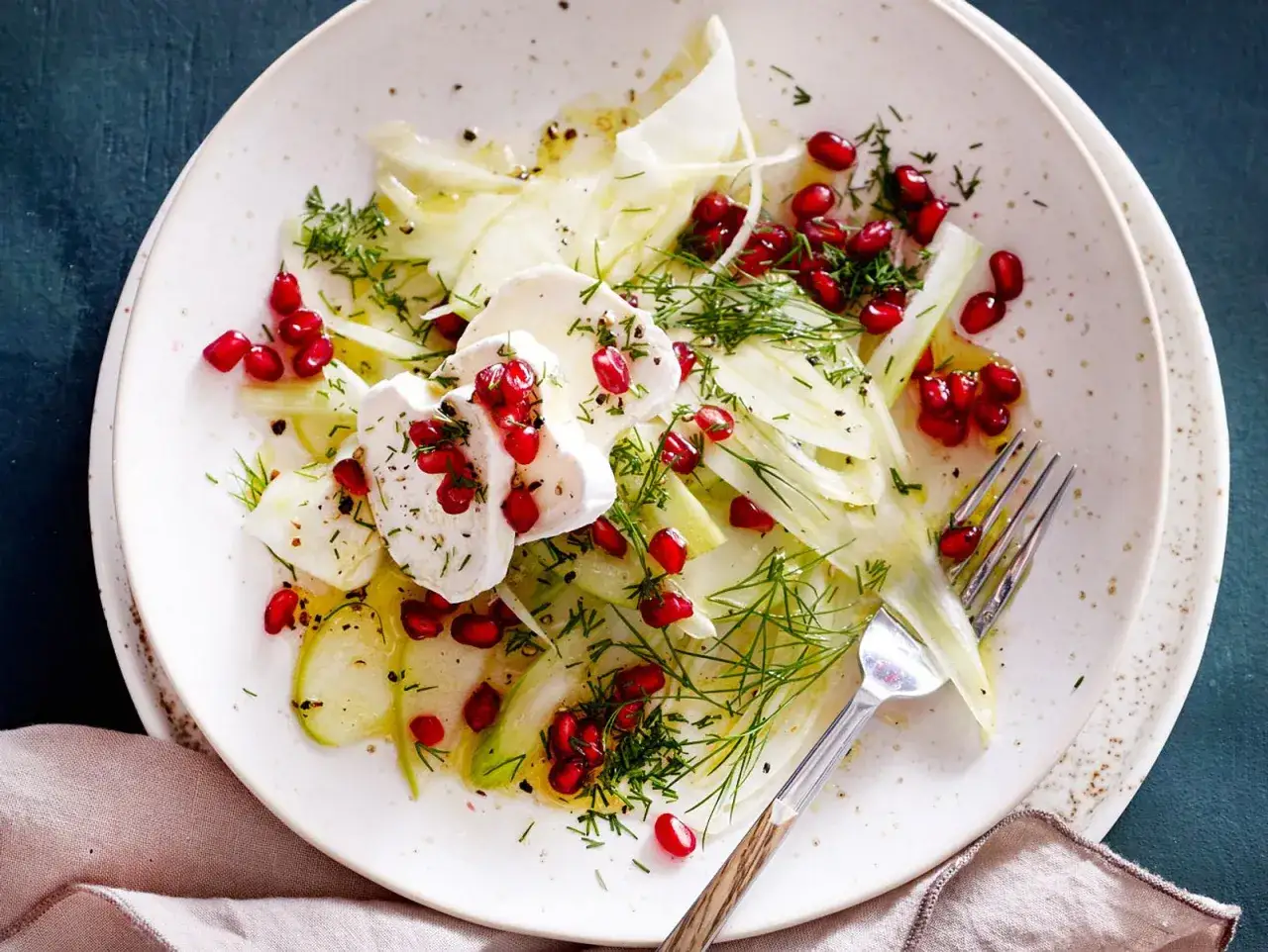 Erfrischender Fenchel Apfel Salat mit Granatapfelkernen und Ziegenkäse, garniert mit Dill.