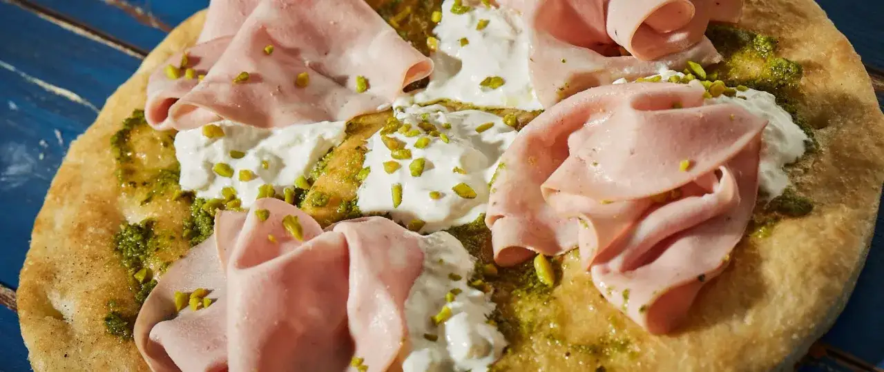 Pizza mit Mortadella, cremiger Burrata, Pesto und gehackten Pistazien. Ein Genuss f&uuml;r alle Sinne!