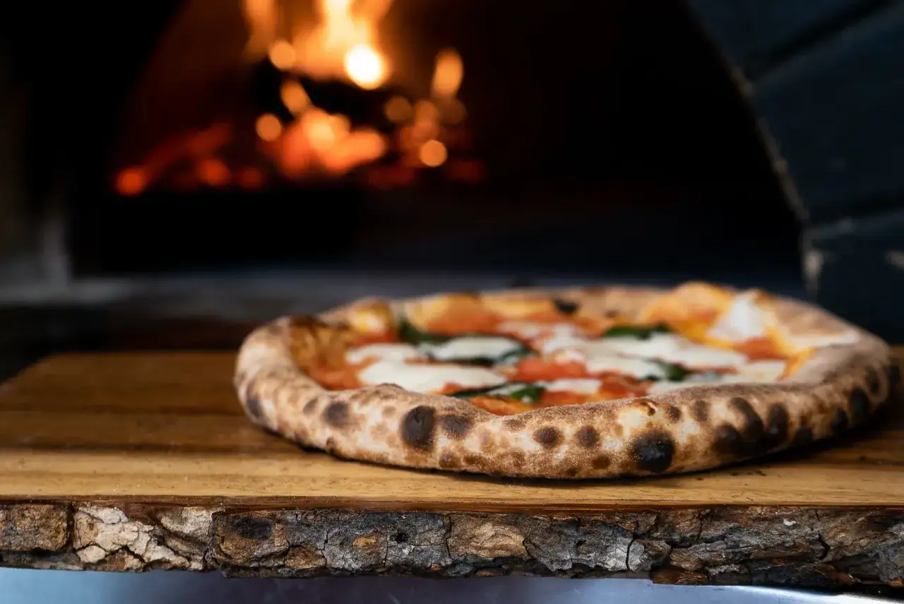 Eine original Pizza mit Mozzarella und Tomaten, frisch aus dem Holzofen.