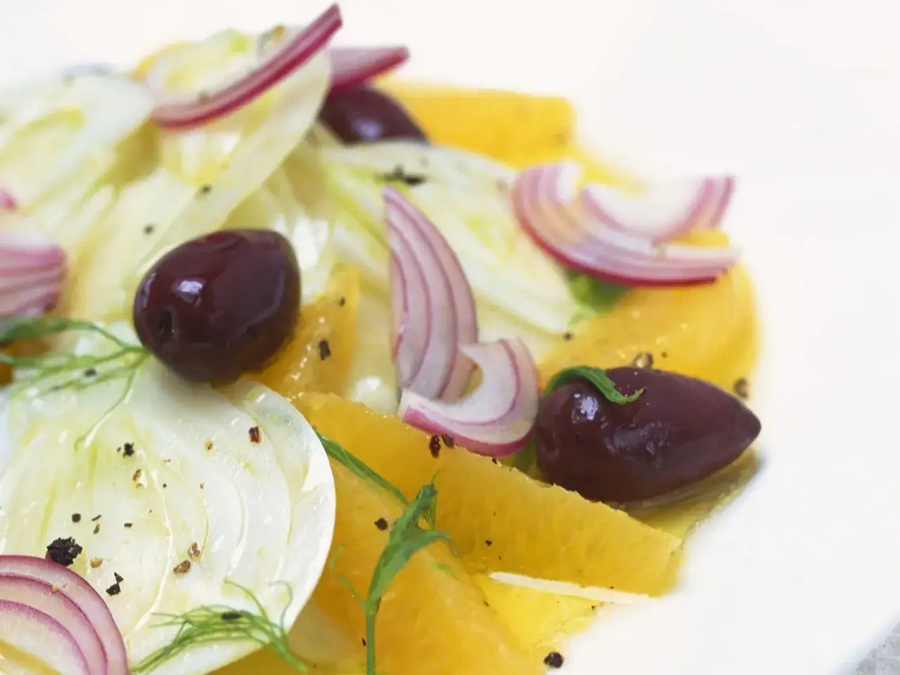 Frischer Fenchel Salat mit Orangen, roten Zwiebeln und Kalamata-Oliven, garniert mit Dill und schwarzem Pfeffer.