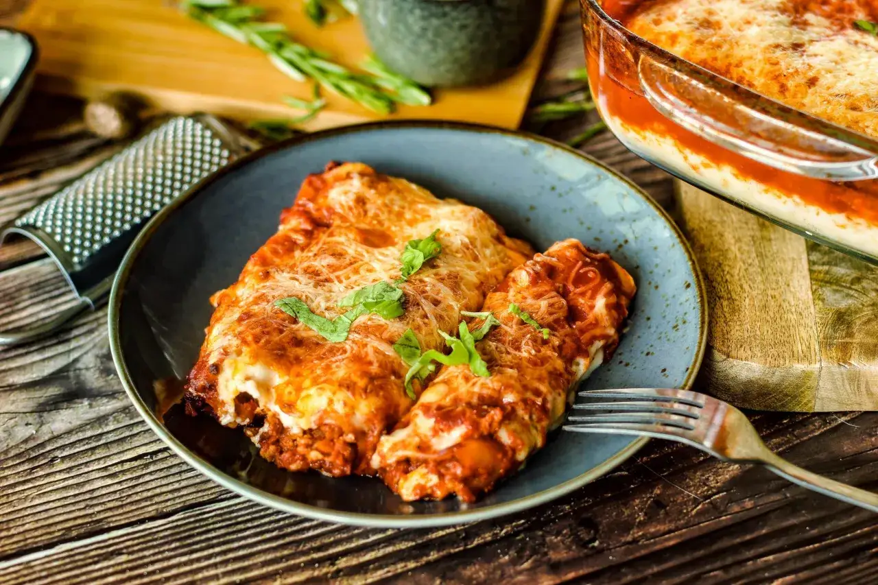 Ein Teller mit leckeren Cannelloni, &uuml;berbacken mit K&auml;se und Tomatensauce. Ein k&ouml;stliches Cannelloni Rezept, das zum Nachkochen einl&auml;dt.