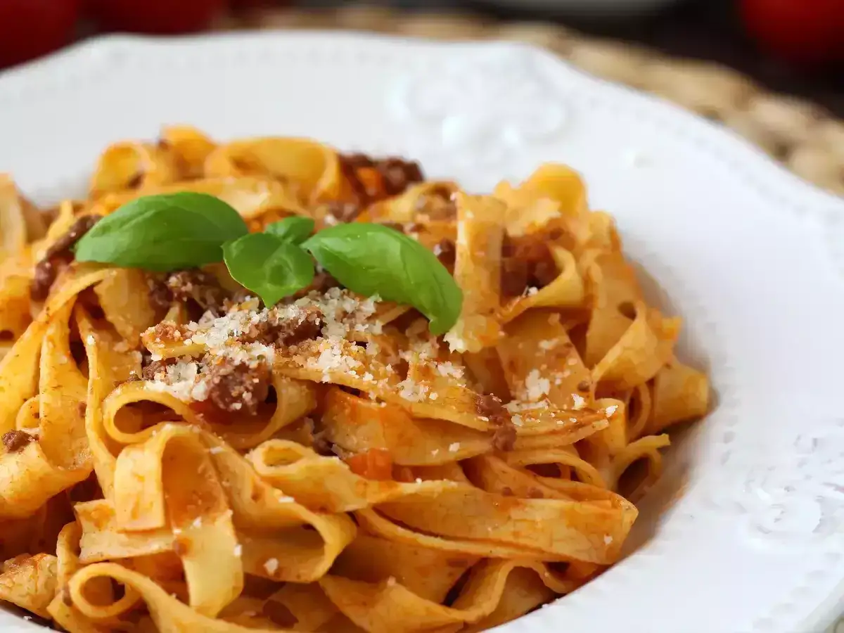 Ein Teller mit original italienischer Bolognese, garniert mit frischem Basilikum und Parmesan.