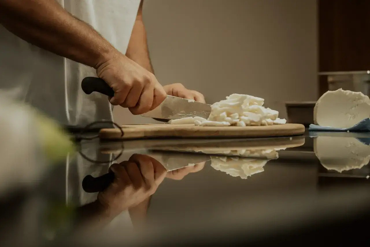 H&auml;nde schneiden Fior di Latte f&uuml;r das Einfrieren. Der K&auml;se wird in kleine St&uuml;cke zerteilt, um ihn sp&auml;ter zu verwenden.