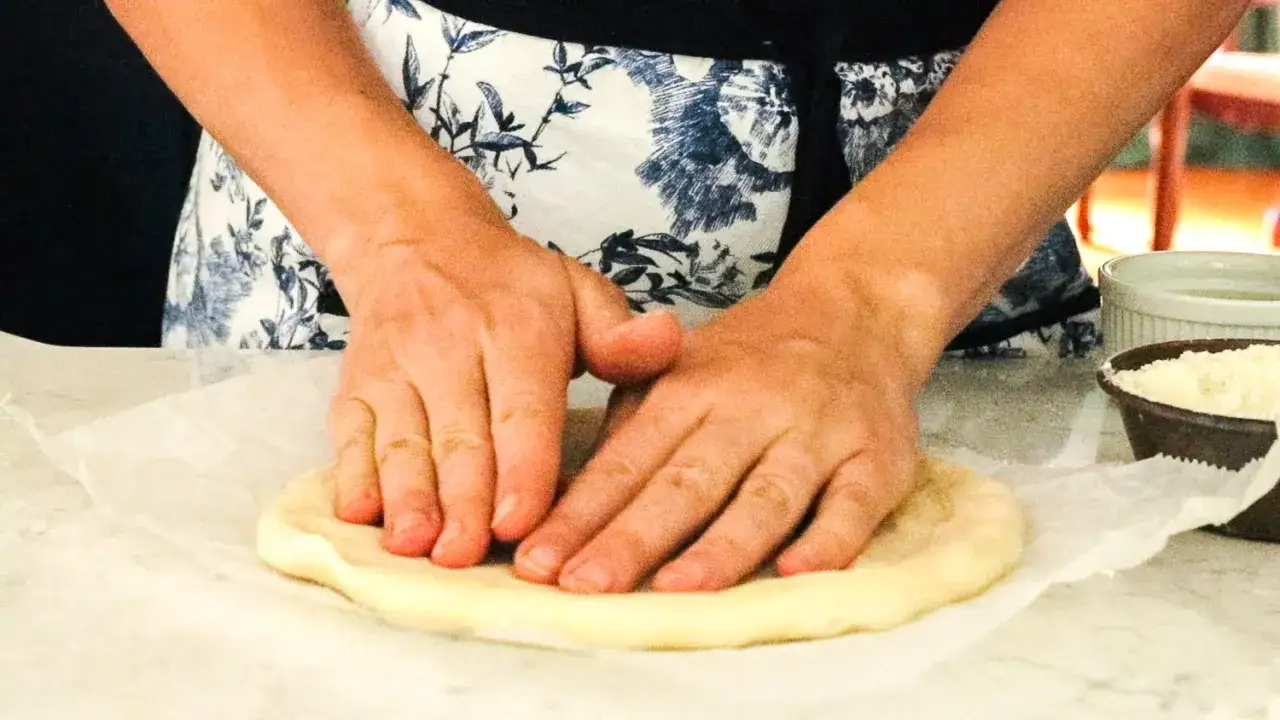 H&auml;nde kneten Pizzateig auf Backpapier. Die Frage 