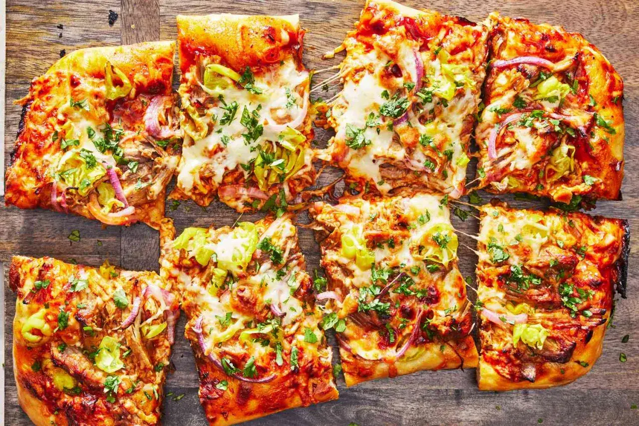 Verschiedene Pizza-Sorten mit geschmolzenem Käse, pulled pork, Zwiebeln und Paprika, bestreut mit frischer Petersilie.